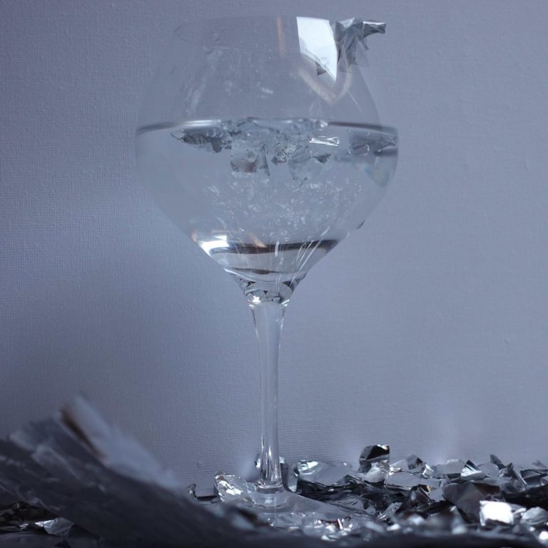 Leharim Verre rempli d'eau sur un fond sombre avec des reflets métalliques.